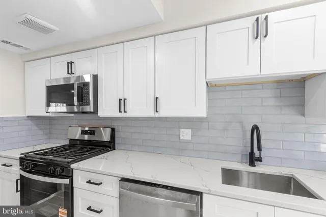 a kitchen with white cabinets and appliances