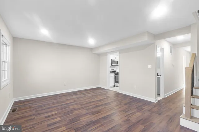 an empty room with wooden floor & windows and bathroom