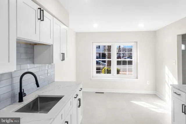 a view of a kitchen sink with white cabinets