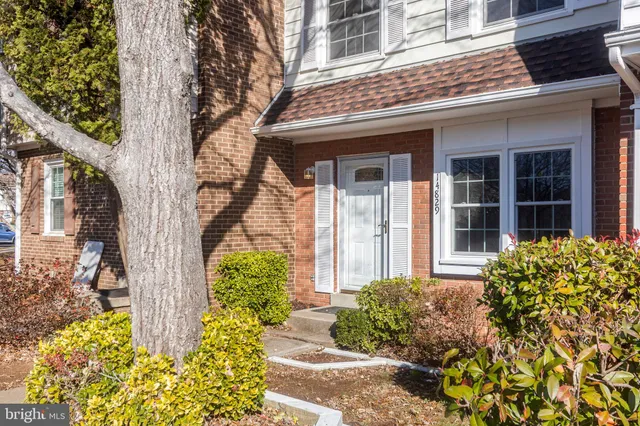 front view of a brick house with a large tree