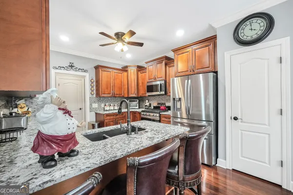 a kitchen with stainless steel appliances granite countertop a refrigerator a sink dishwasher a stove and white countertops with wooden floor