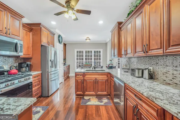 a kitchen with granite countertop a table chairs a sink and dishwasher a refrigerator with wooden floor