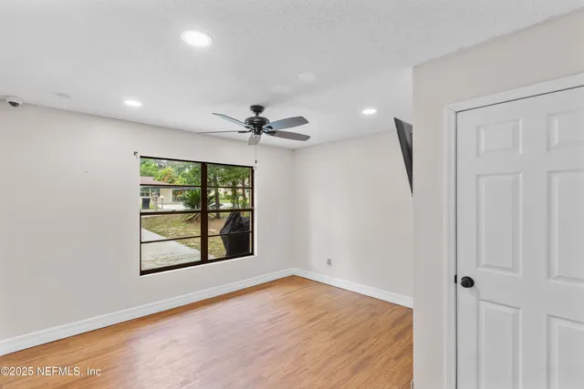 an empty room with wooden floor and windows