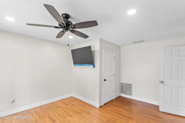 a view of a hallway with wooden floor and a ceiling fan