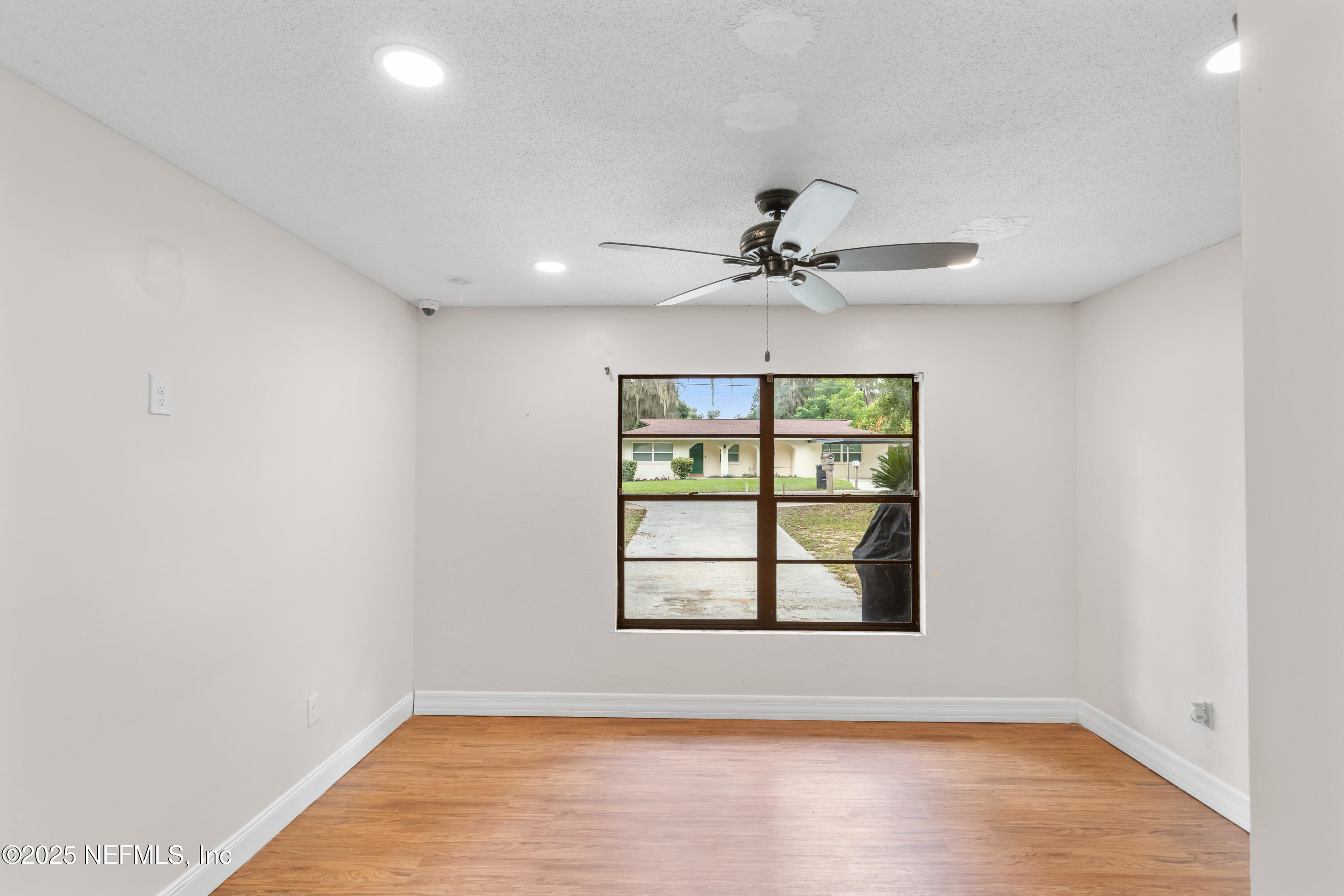 220 Southwest Grove Street Keystone Heights, FL 32656 - Photo 19 of 41 an empty room with wooden floor chandelier fan and windows