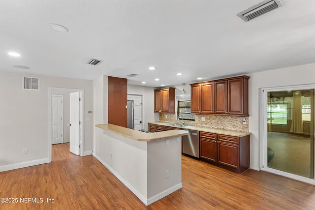 a large kitchen with stainless steel appliances granite countertop a large counter top and a wooden floors