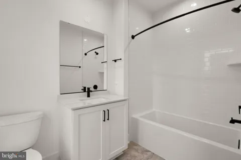 a bathroom with a granite countertop sink mirror toilet and bathtub