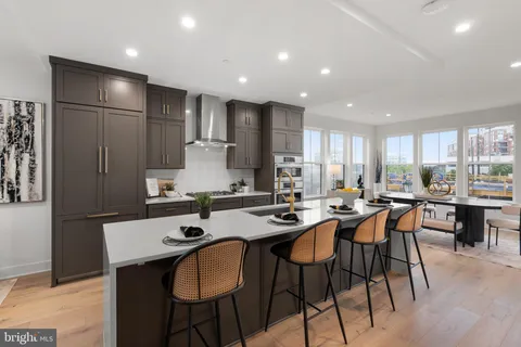 a kitchen with stainless steel appliances granite countertop a table chairs sink and white cabinets
