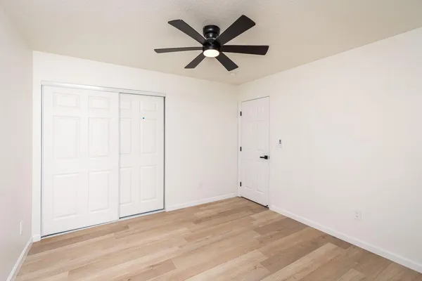 an empty room with wooden floor and ceiling fan