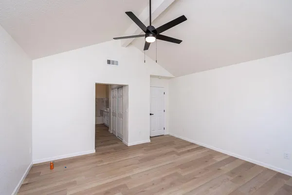 an empty room with wooden floor and ceiling fan