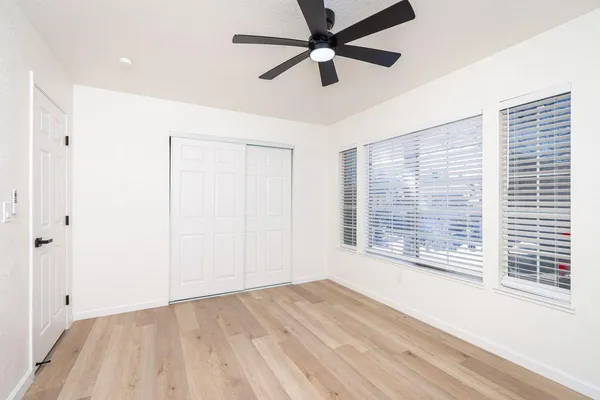 a view of an empty room with a window and wooden floor