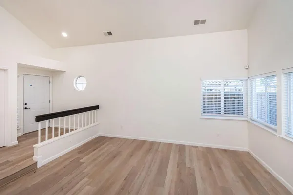 a view of an empty room with wooden floor and a window