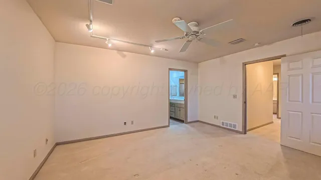 an empty room with a chandelier fan and windows
