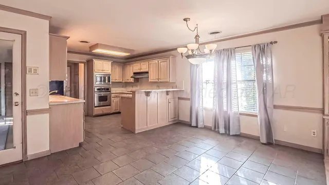 a kitchen with white cabinets and chandelier