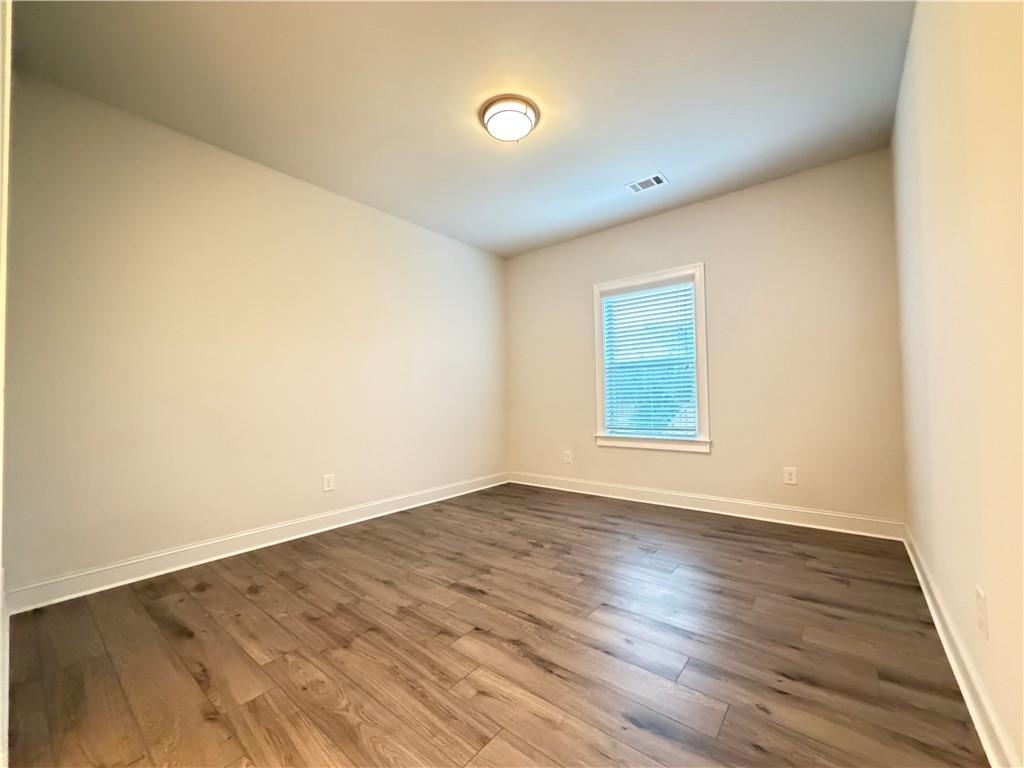 1545 Dahlia Drive Cumming, GA 30040 - Photo 36 of 50 a view of an empty room with wooden floor and a window
