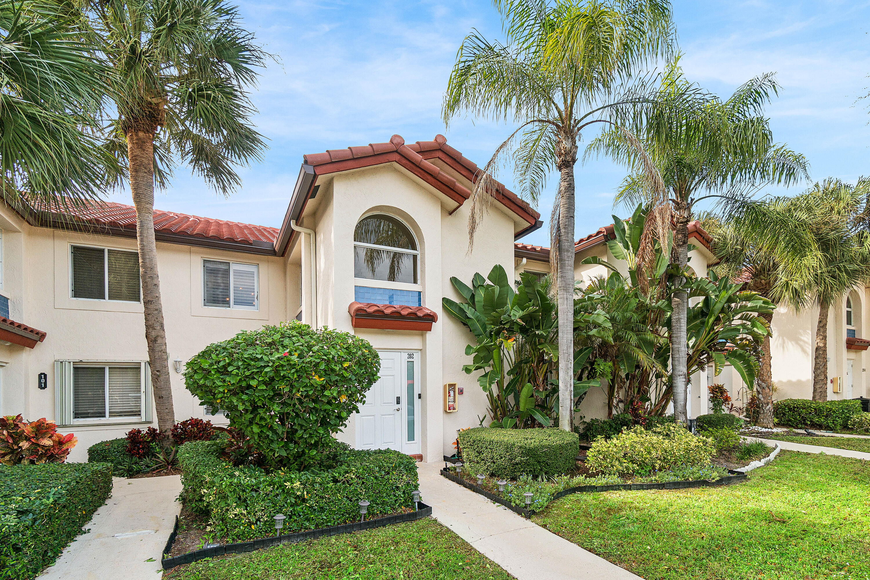 340 Northwest 67th Street, Unit 202 Boca Raton, FL 33487 - Photo 2 of 39 a front view of a house with a garden
