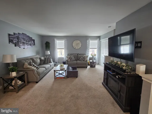 a living room with furniture a clock on wall and a window