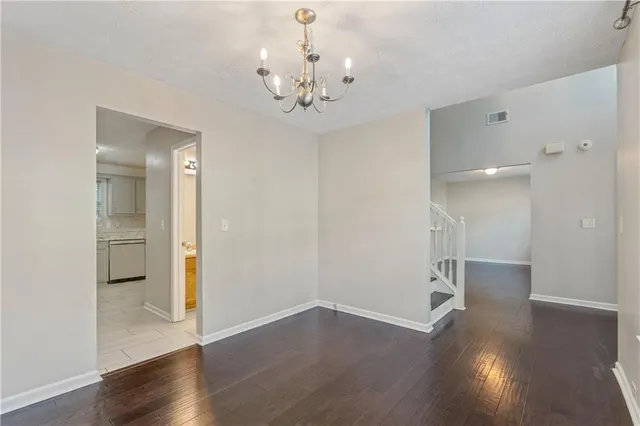 a view of an empty room with wooden floor and a chandelier