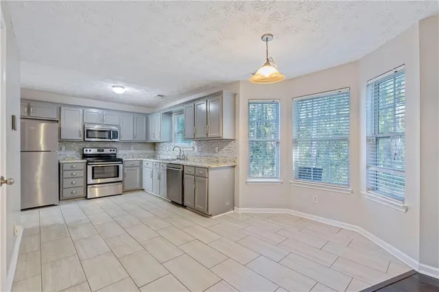 a kitchen with stainless steel appliances granite countertop a stove a sink dishwasher a refrigerator and white cabinets with wooden floor