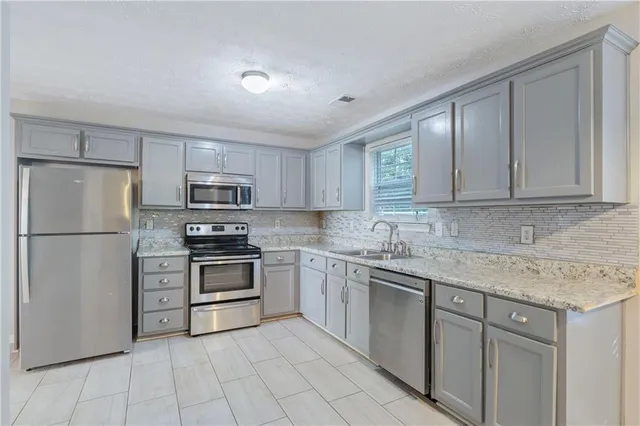 a kitchen with stainless steel appliances granite countertop a refrigerator sink and stove