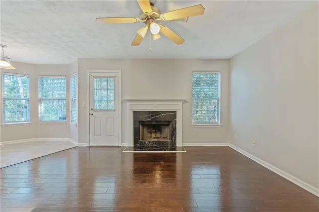 an empty room with windows fireplace and wooden floor