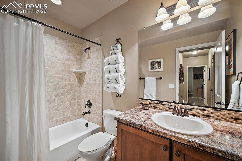 12988 Cupcake Heights Colorado Springs, CO 80921 - Photo 30 of 39 a bathroom with a granite countertop sink a toilet a mirror a bathtub and shower