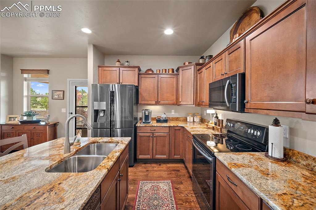 12988 Cupcake Heights Colorado Springs, CO 80921 - Photo 9 of 39 a kitchen with kitchen island granite countertop a sink stove and refrigerator