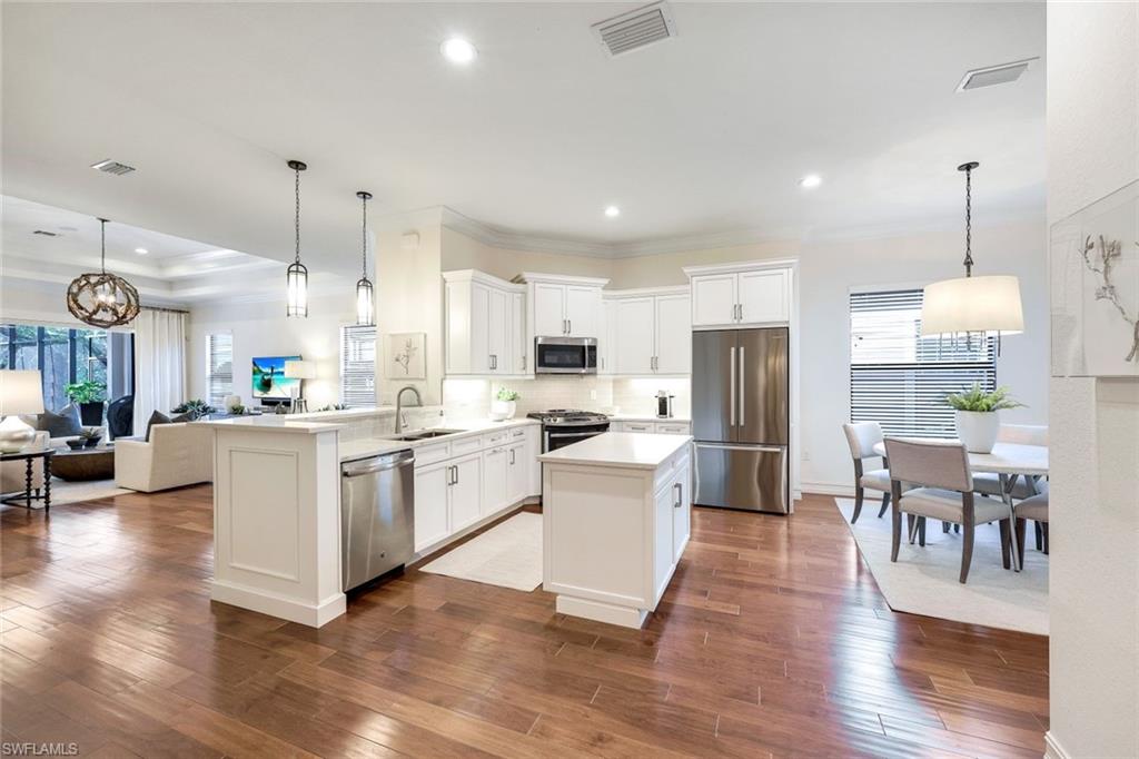 6573 Roma Way Naples, FL 34113 - Photo 13 of 49 Kitchen with dark wood-type flooring, sink, kitchen peninsula, pendant l