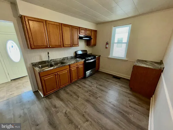 a kitchen with stainless steel appliances granite countertop a stove a sink dishwasher and a microwave oven with wooden cabinets