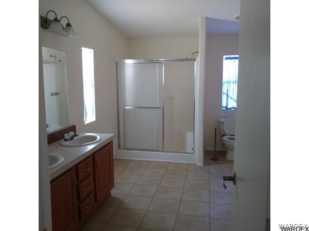 586 Bacobi Road Golden Valley, AZ 86413 - Photo 26 of 36 a bathroom with a granite countertop sink a toilet and a mirror