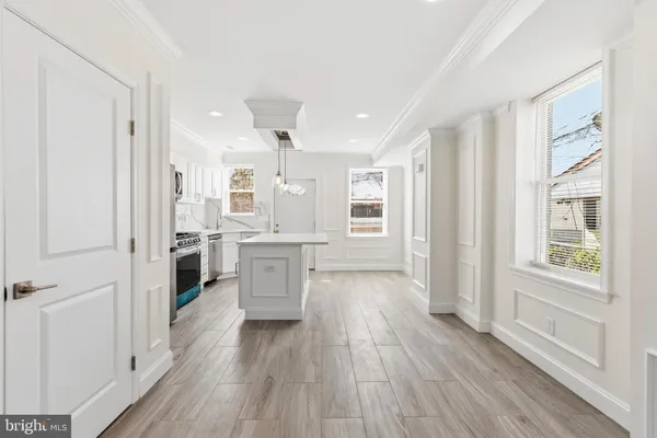 a view of a hallway with wooden floor and a kitchen
