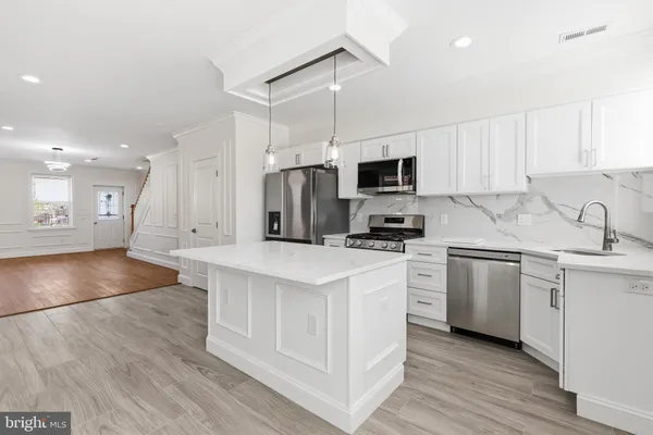 a kitchen with granite countertop a sink a counter top space stainless steel appliances and cabinets