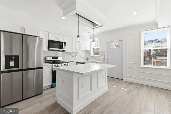 a kitchen with kitchen island granite countertop a sink appliances cabinets and a counter space