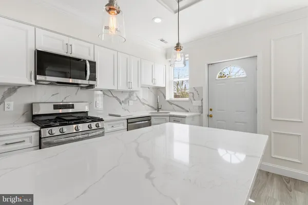 a living room with stainless steel appliances a fireplace a flat screen tv and a window