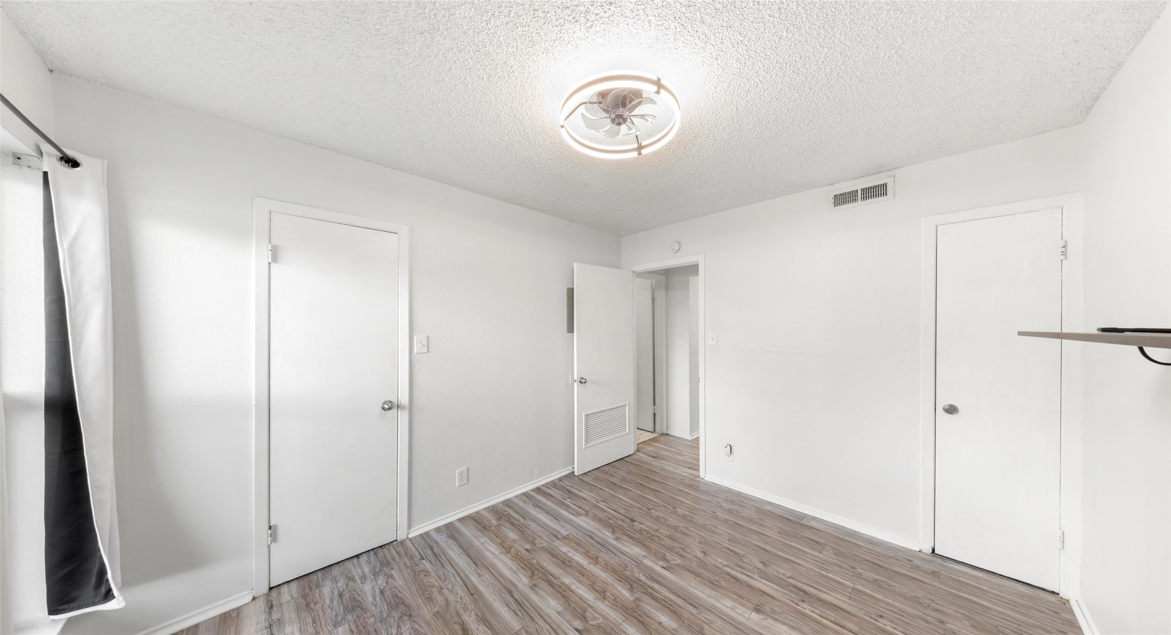 2401 Manor Road, Unit 123 Austin, TX 78722 - Photo 14 of 22 Well-lit room featuring durable wood-like flooring and a modern ceiling light fixture.