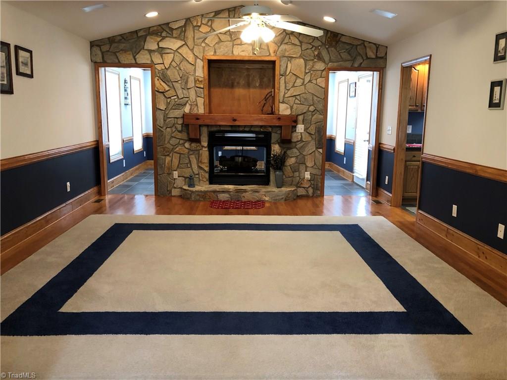 261 Running Creek Road Browns Summit, NC 27214 - Photo 5 of 28 Spacious Great Room where you can get away without going away. Stone see thru fireplace surrounded by beautiful stone wood, vaulted ceilings and warm wood floors. Mantel is a recycled old beam. Opens into the Sunroom.