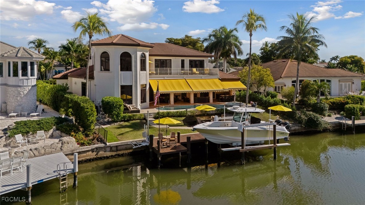 361 Pirates Bight Naples, FL 34103 - Photo 11 of 33 a white house with a large pool and lawn chairs under an umbrella