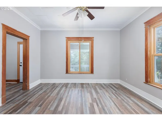 a view of an empty room with wooden floor fireplace and a window
