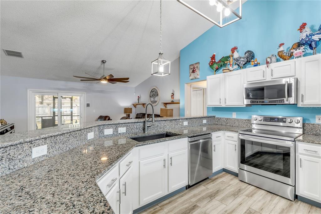 7 Ranbay Place Palm Coast, FL 32164 - Photo 16 of 76 a kitchen with stainless steel appliances granite countertop a sink a stove a microwave and wooden cabinets