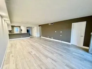 a view of a livingroom with wooden floor and kitchen space