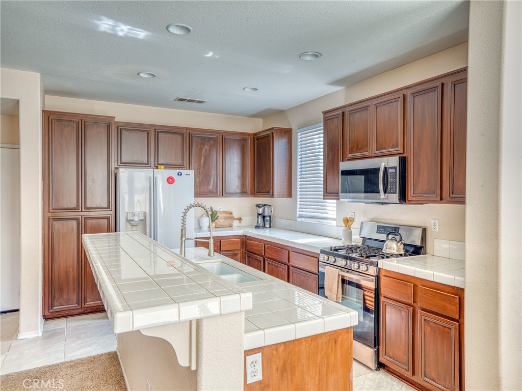 39233 Chantilly Lane Palmdale, CA 93551 - Photo 12 of 31 a kitchen with stainless steel appliances granite countertop a stove a sink dishwasher a microwave oven and a refrigerator with wooden cabinets
