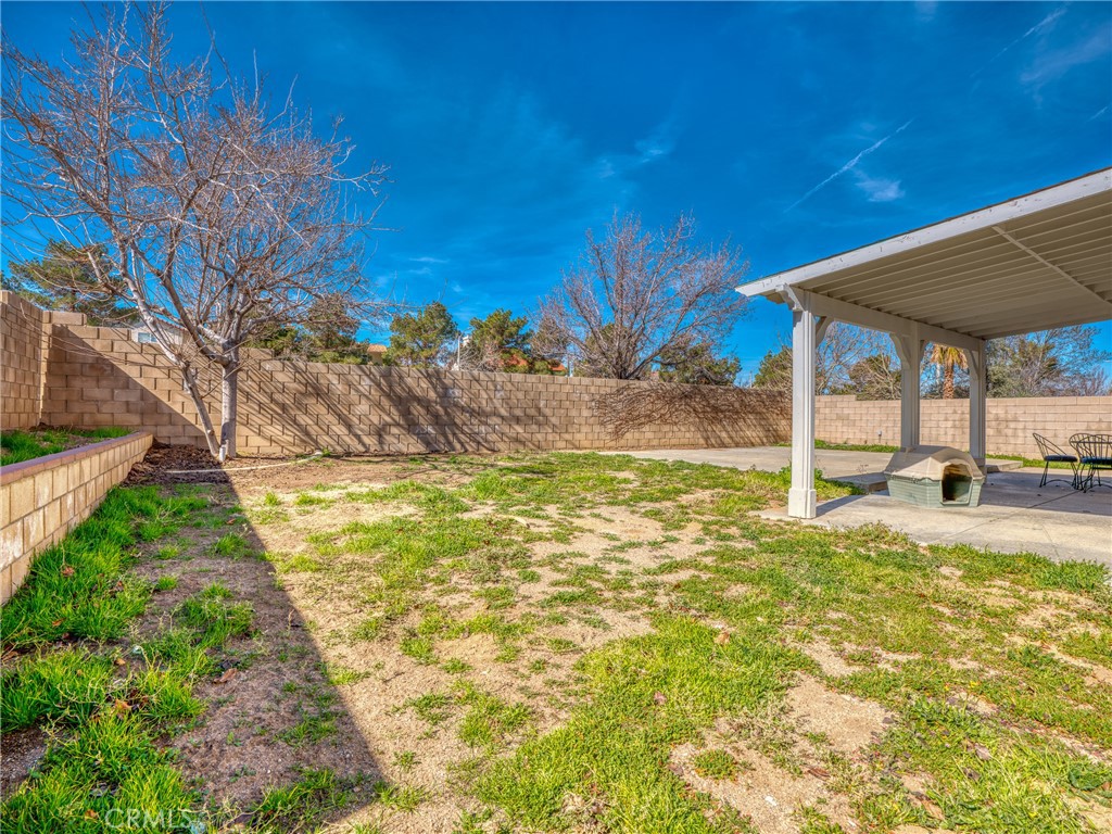 39233 Chantilly Lane Palmdale, CA 93551 - Photo 27 of 31 a view of a backyard with table and chairs under an umbrella