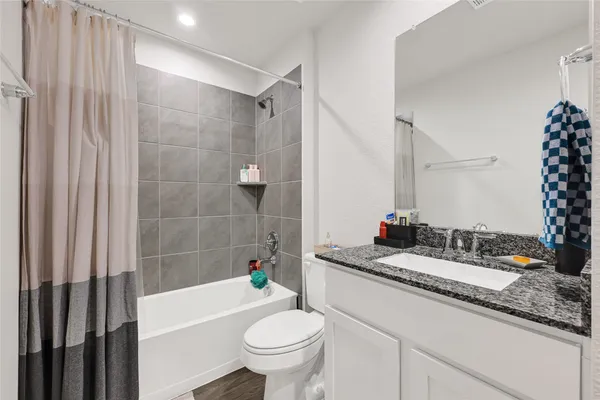 a bathroom with a granite countertop sink toilet mirror and bathtub