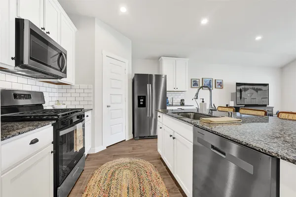 a kitchen with stainless steel appliances granite countertop a stove a sink and a refrigerator
