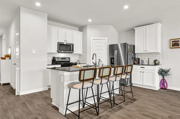 a kitchen with stainless steel appliances a refrigerator stove microwave and white cabinets