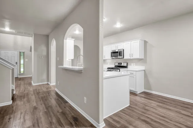 a kitchen with cabinets and wooden floor