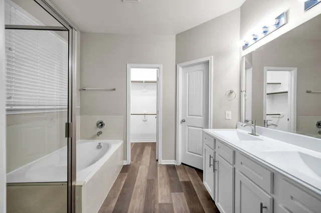 a spacious bathroom with a tub sink and mirror