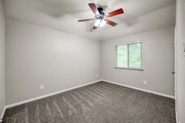 en empty room with windows and chandelier fan