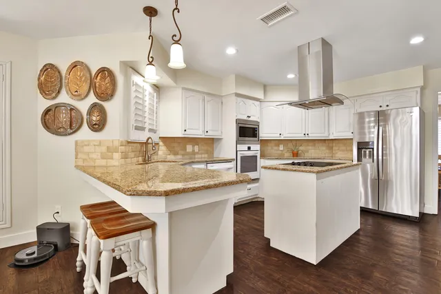 a kitchen with kitchen island granite countertop a stove and a sink
