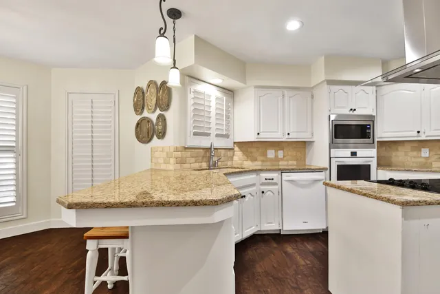 a kitchen with kitchen island granite countertop a sink a counter space appliances and cabinets